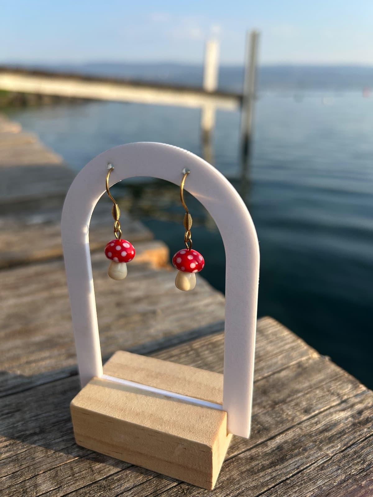 Boucles d'oreilles pendantes en verre en forme de champignons rouges à pois blancs sur présentoir