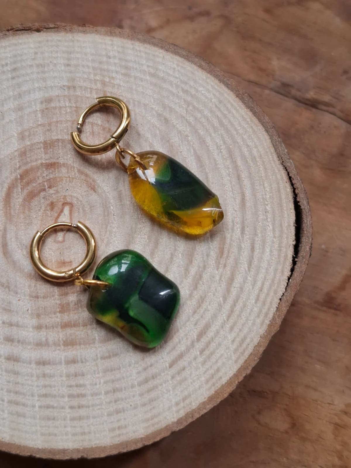 Boucles d'oreilles en verre vert et jaune aux formes organiques posées sur une rondelle de bois