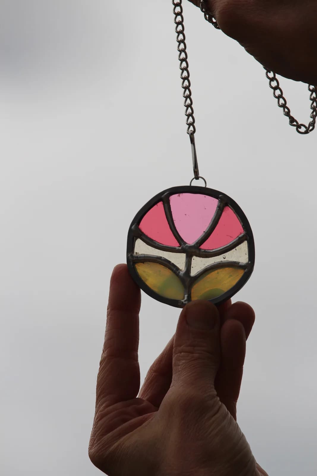 Suspension vitrail circulaire ornée d'une fleur stylisée rose et vert