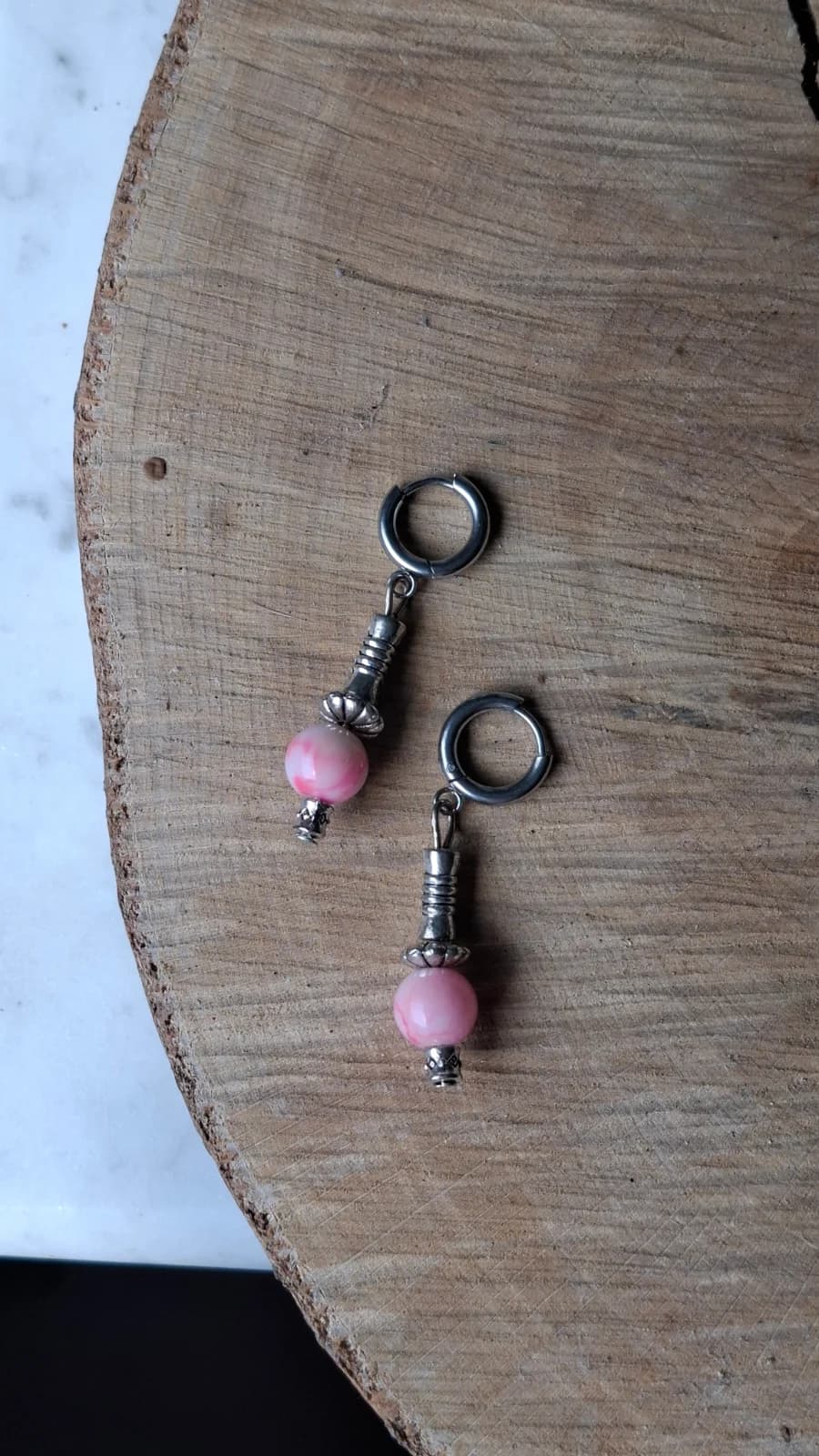 Paire de boucles d'oreilles pendantes à perles marbrées roses et pampilles métalliques suspendues.