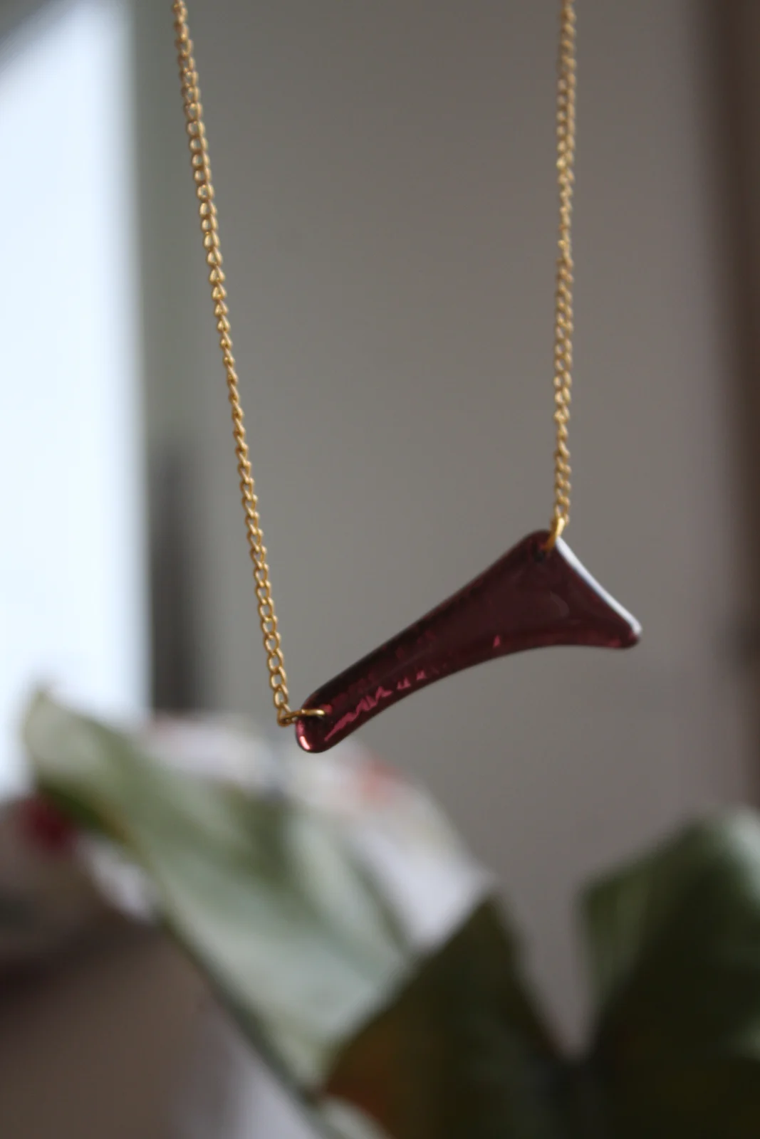 Pendentif asymétrique en verre bordeaux suspendu à une fine chaîne dorée