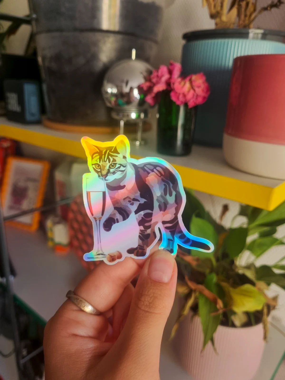 Sticker holographique illustrant un chat tigré avec un verre à pied et un bouchon tenu en main