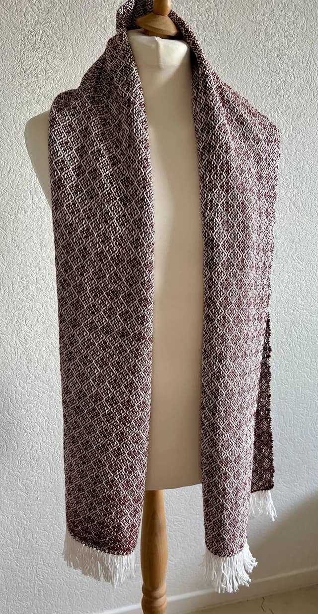 Écharpe tissée bordeaux et blanche à motifs losanges et franges, présentée sur un mannequin