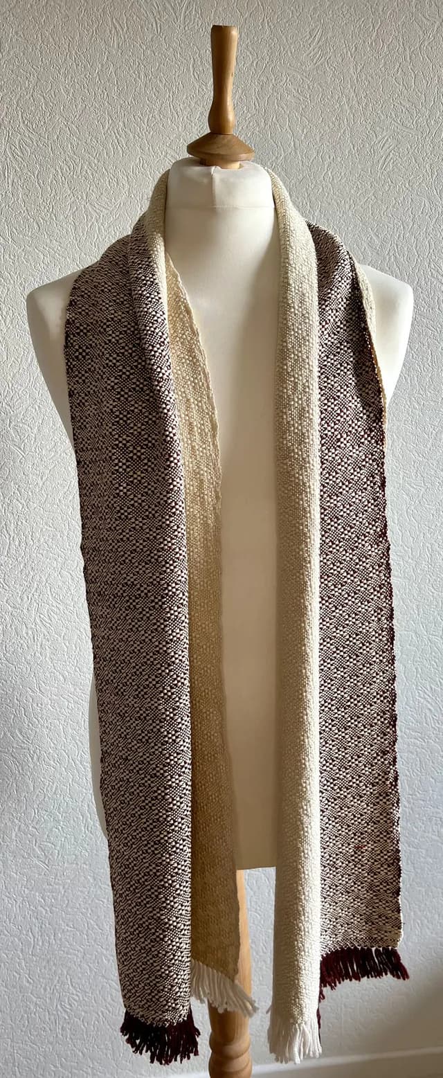 Écharpe tissée bicolore bordeaux et écru avec franges, drapée sur un mannequin.