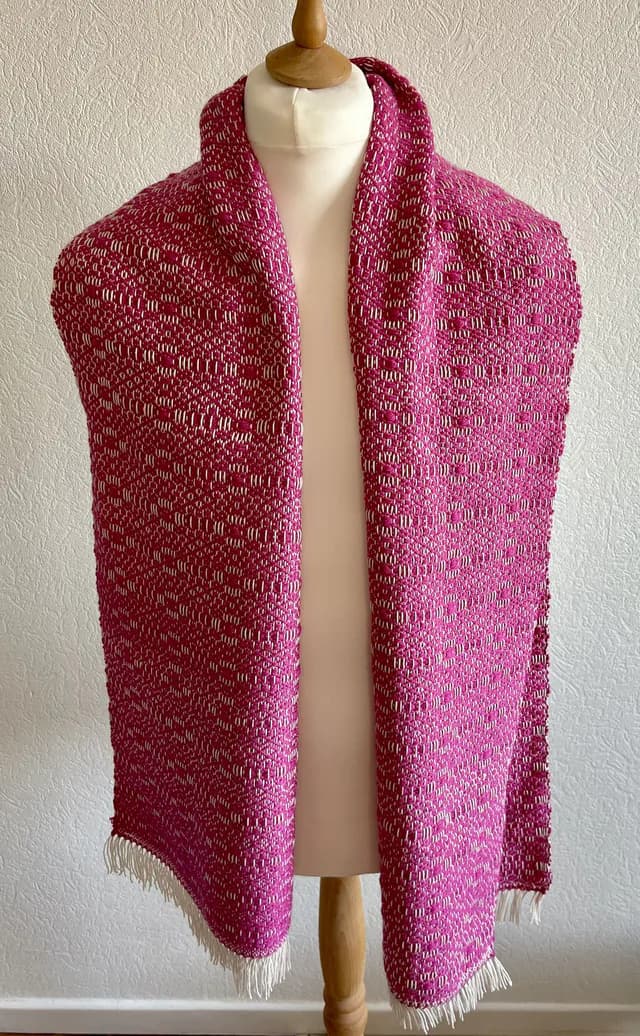 Écharpe tissée rose framboise et blanche avec petites franges, présentée sur un buste de mannequin.