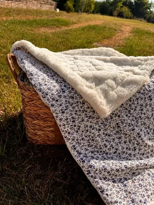 Couverture bébé à motif de petites fleurs posée sur un lit à barreaux sous un mobile d'éveil