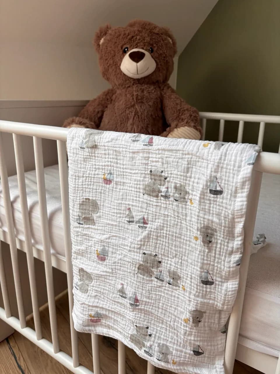 Lange blanc en gaze de coton à motifs oursons posé sur un lit à barreaux blanc avec peluche
