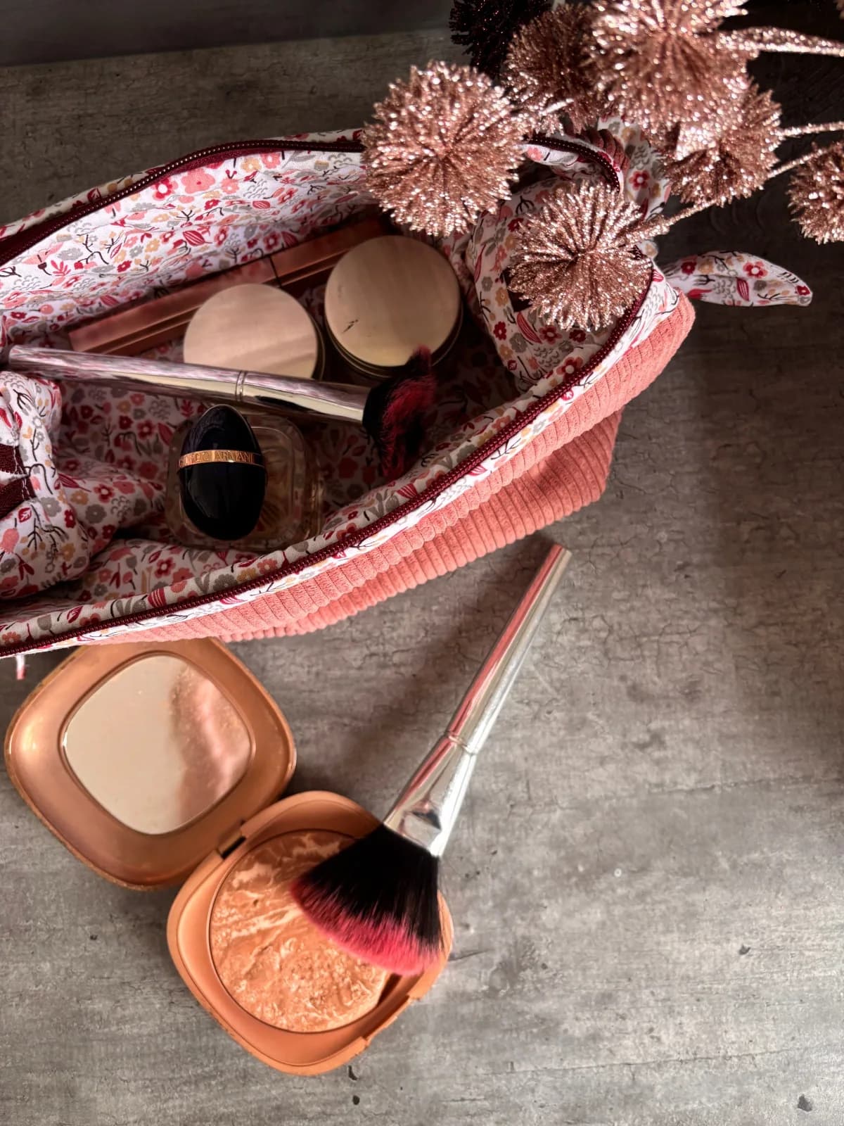 Trousse en velours côtelé rose ouverte avec doublure fleurie et accessoires de beauté