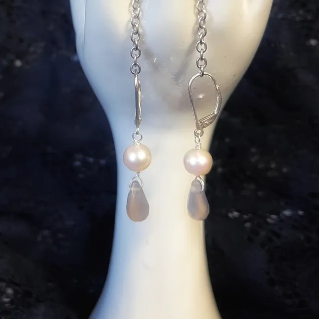 Gros plan sur les boucles d'oreilles avec perle blanche ronde et goutte d'agate facettée sur dormeuse argentée.