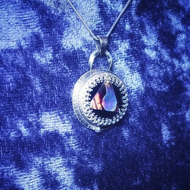 Pendentif rond avec nacre triangulaire et bordure ciselée sur tissu bleu