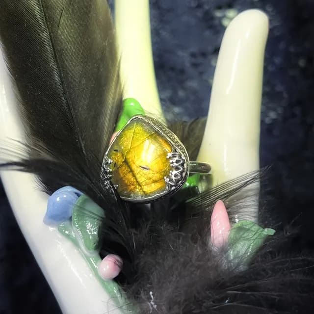 Bague en argent avec pierre labradorite triangulaire aux reflets dorés sur présentoir et plume