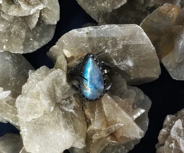 Bague Astra avec pierre de lune taillée en goutte portée à la main, anneau double ciselé.