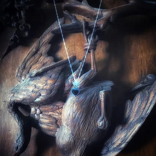 Collier avec pendentif sacré cœur en argent et émail noir suspendu sur une sculpture en bois