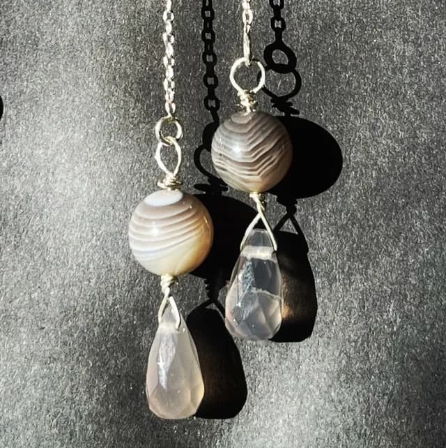 Chaînettes d'oreilles en argent avec perles rondes et gouttes facettées d'agate grise sur fond texturé