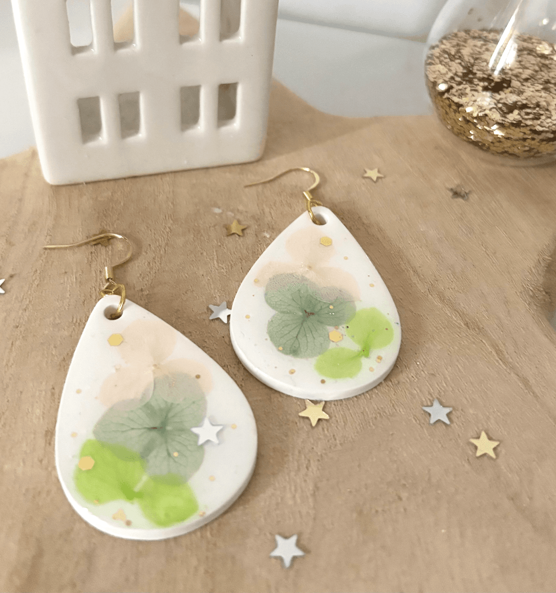 Paire de boucles d'oreilles en goutte blanche aux inclusions de fleurs d'hortensia et paillettes dorées.