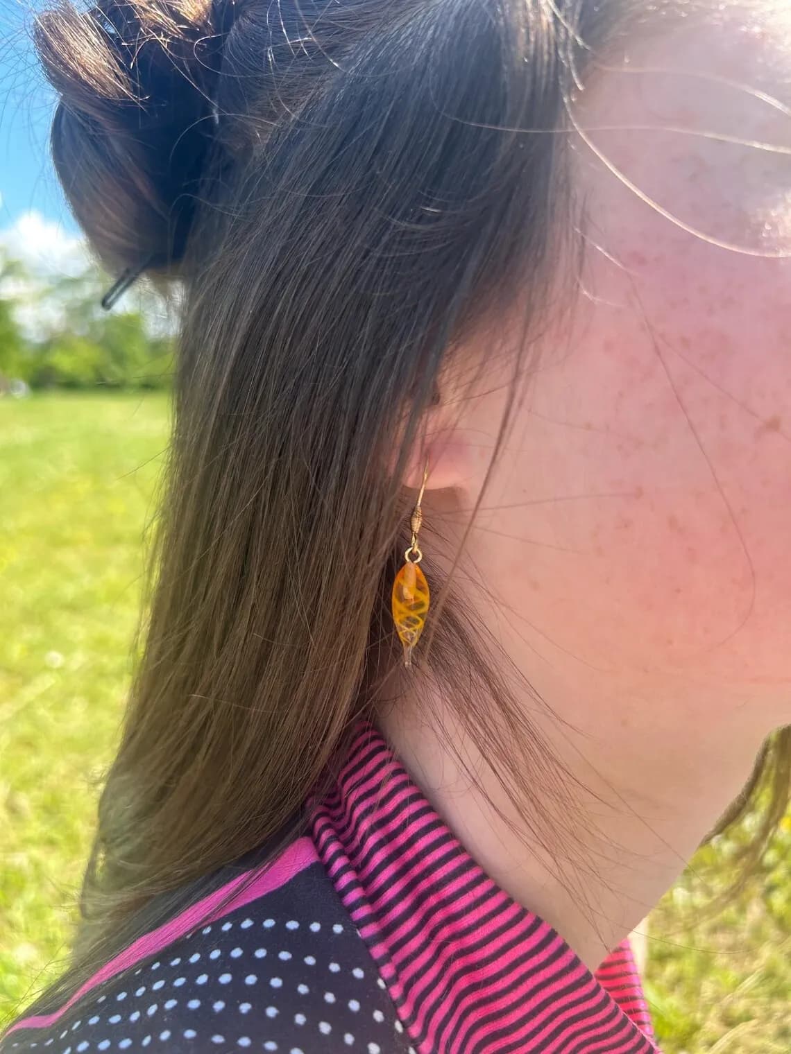 Paire de boucles d'oreilles pendantes en verre orange en forme de gouttes sur présentoir arche.