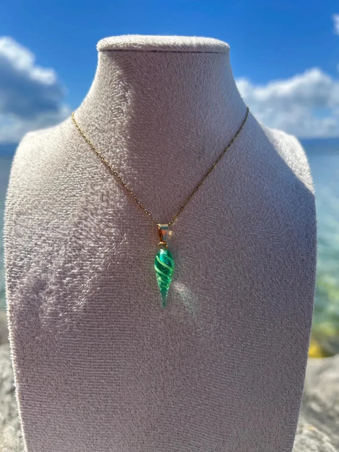 Pendentif coquillage vert torsadé en verre filé sur une fine chaîne dorée sur buste