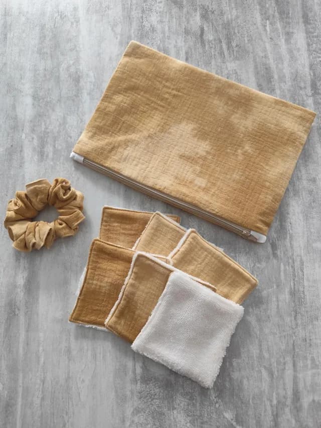 Kit avec pochette zippée jaune moutarde, six lingettes lavables et un chouchou assorti sur fond gris.