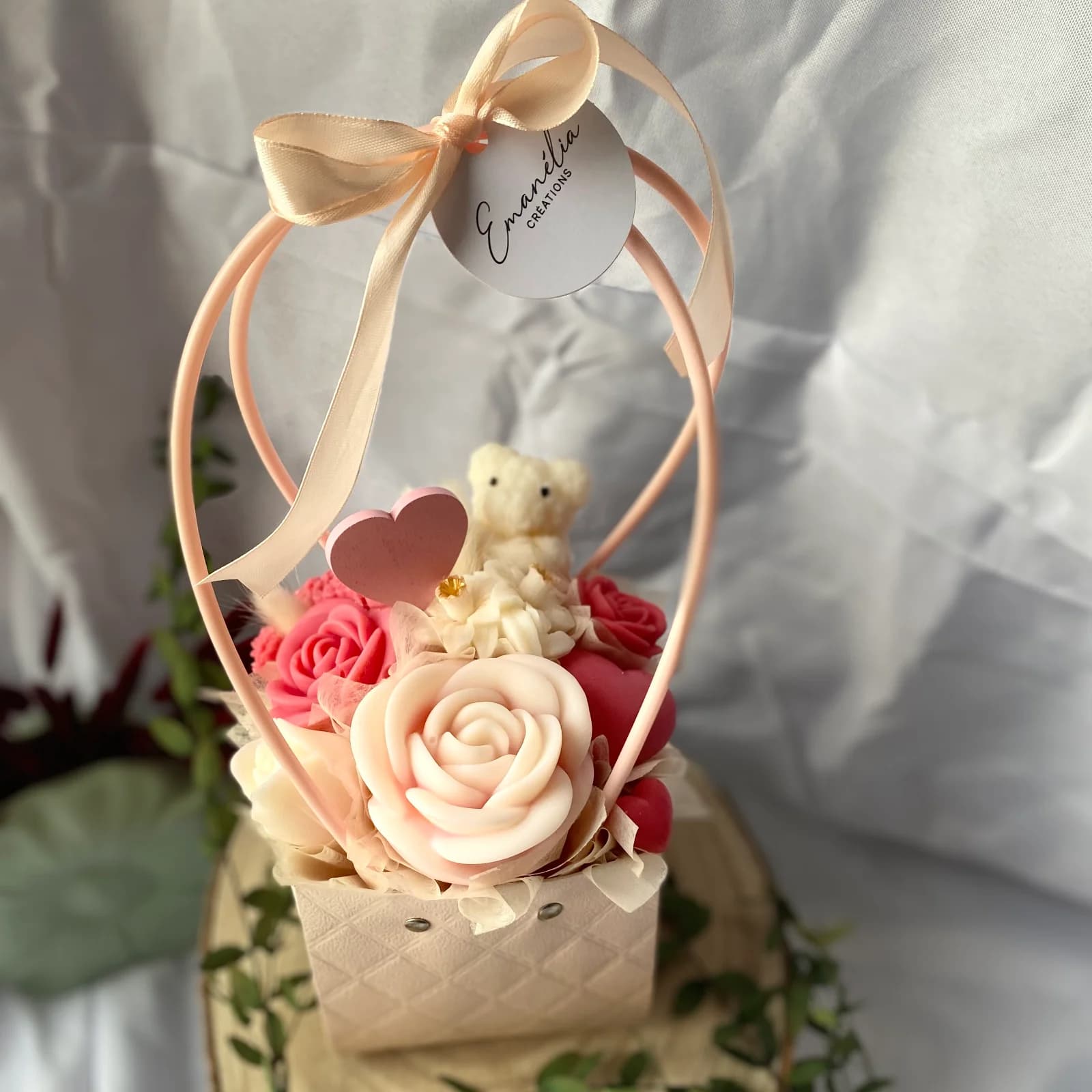Panier fleuri avec roses en cire roses et blanches, petit ourson, cœur rose et anse ruban.