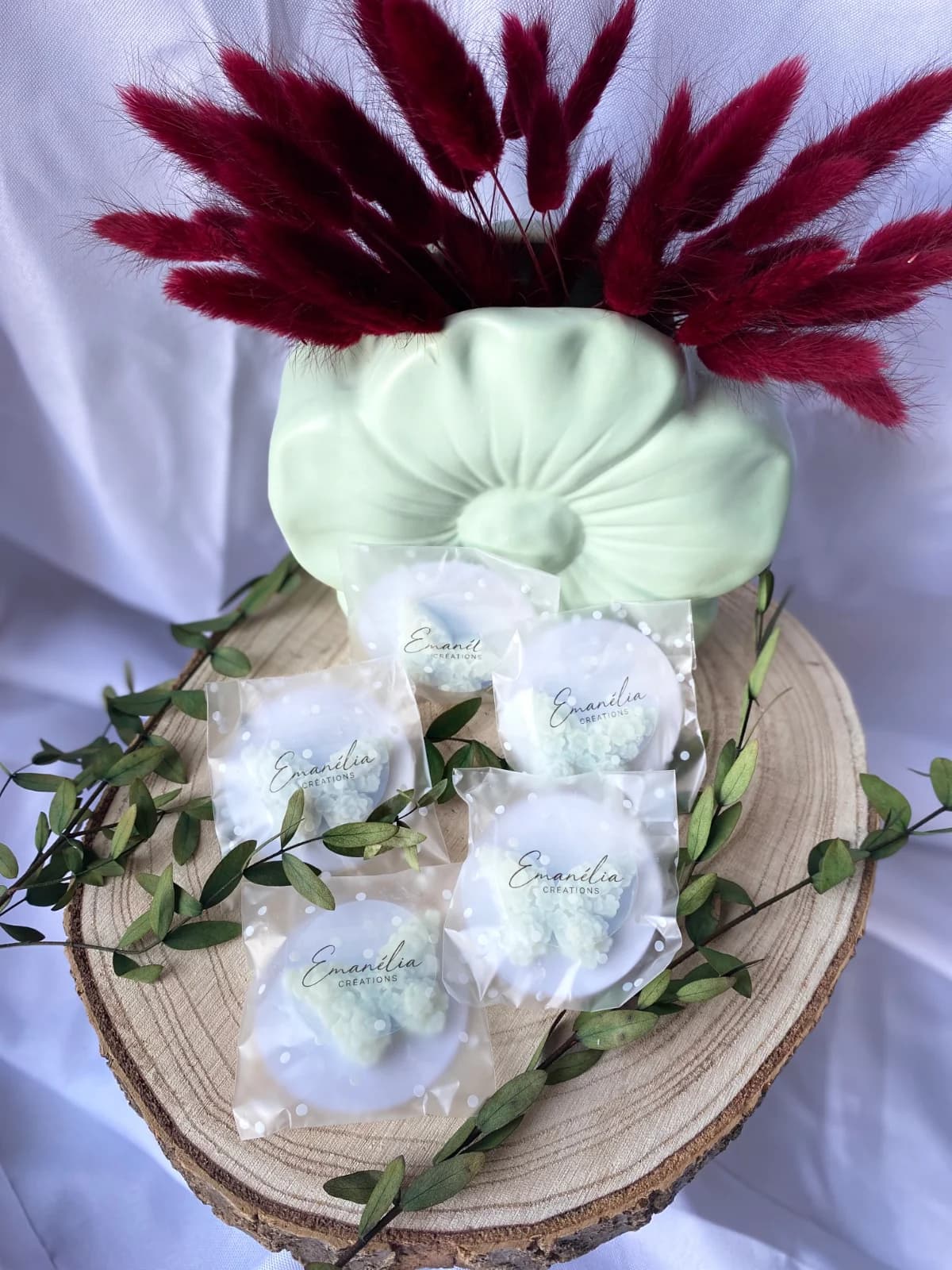 Fondants parfumés en forme de papillon fleuri présentés sur un rondin de bois avec fleurs séchées.