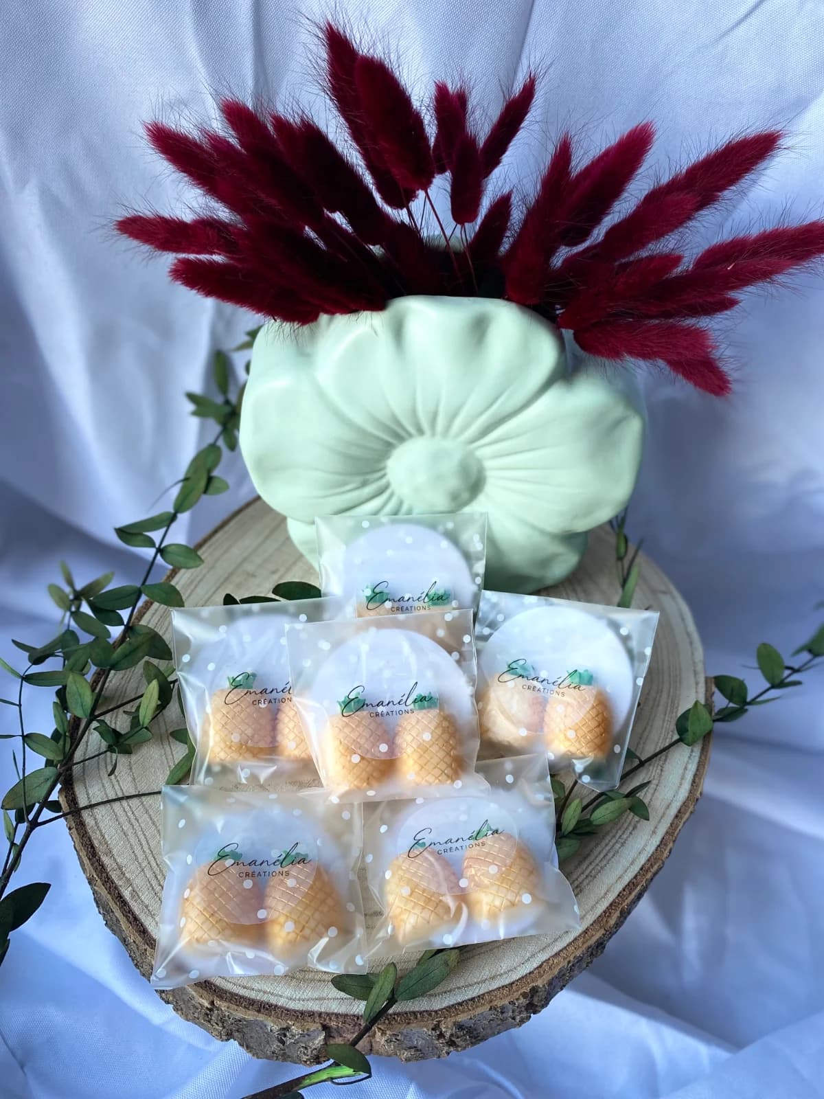 Vue d'ensemble des sachets de fondants ananas présentés sur tranche de bois avec fleurs séchées.