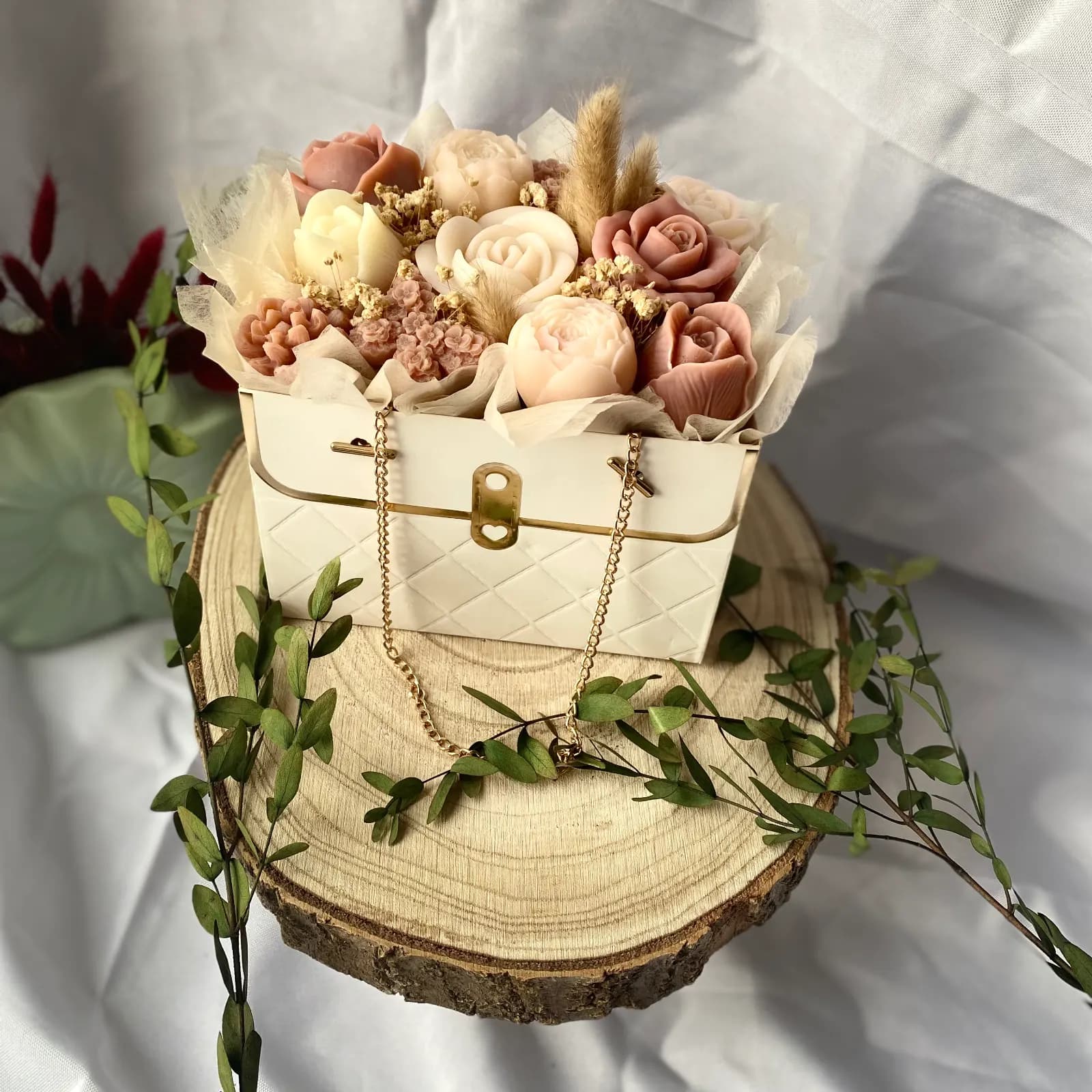 Bouquet Dolce aux fleurs en cire rose poudré et ivoire dans une boîte sacoche blanche.