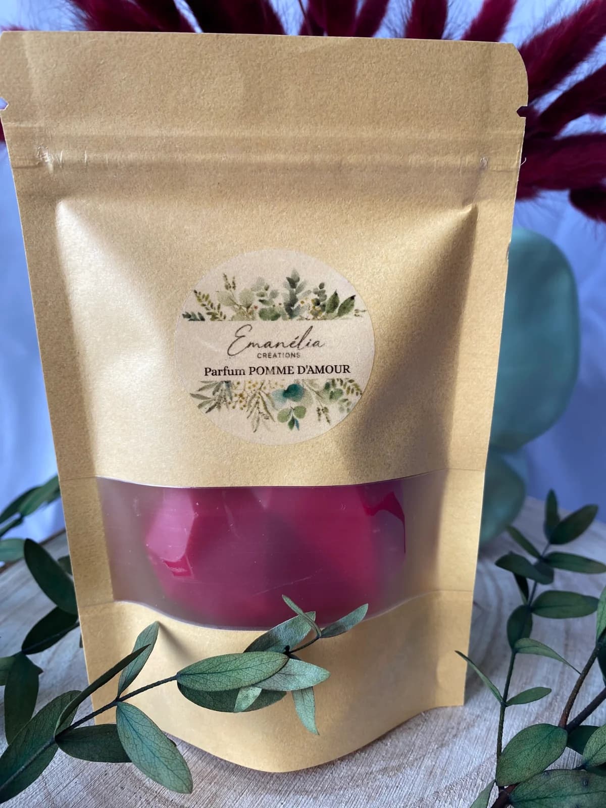 Gros plan sur le sachet kraft avec étiquette Pomme d'amour et fondant parfumé rouge visible par la fenêtre.