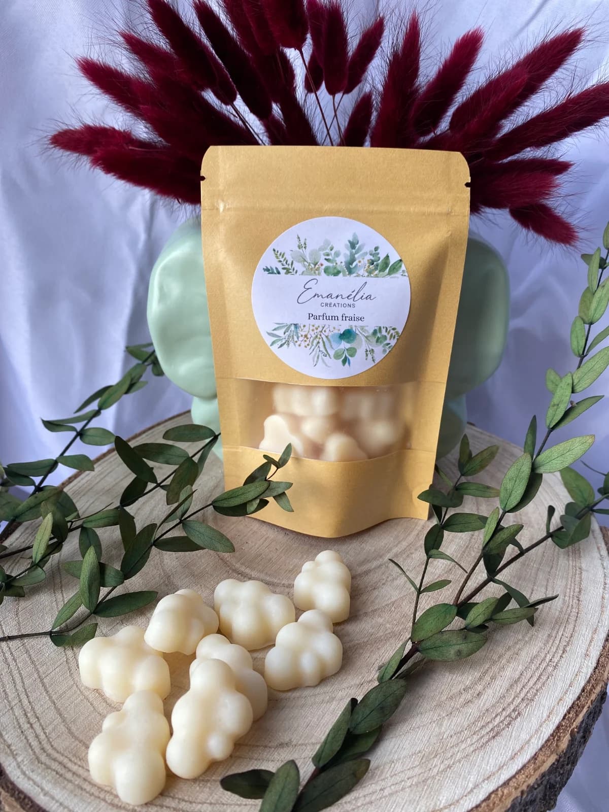 Sachet Emanélia parfum fraise avec ses petits fondants blancs en forme de nuages sur bois.