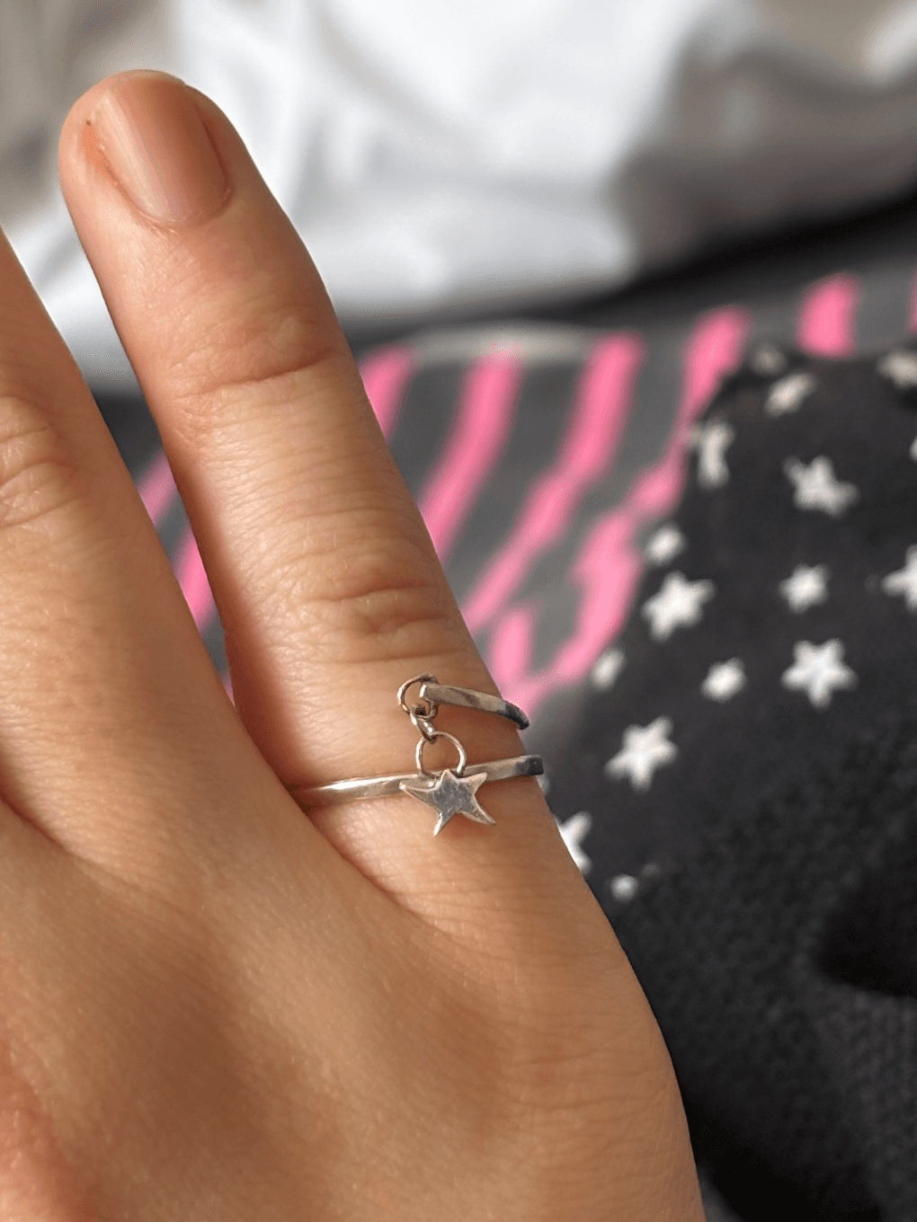 Bague fine ajustable portée au doigt avec une petite breloque en forme d'étoile